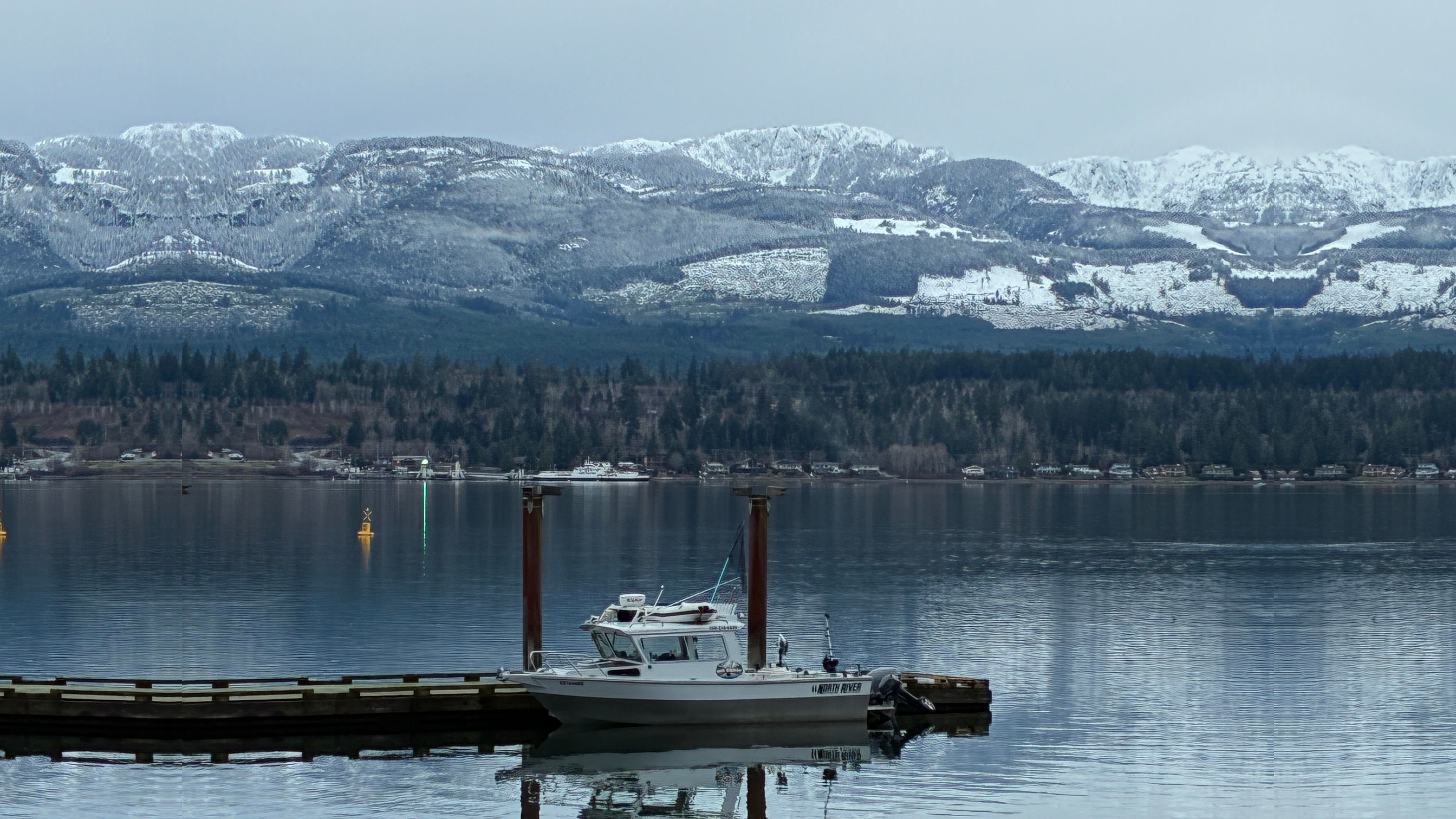 Big Coast Marine Adventures charter boat at the dock with snow-capped mountains across Baynes Sound, Denman Island BC